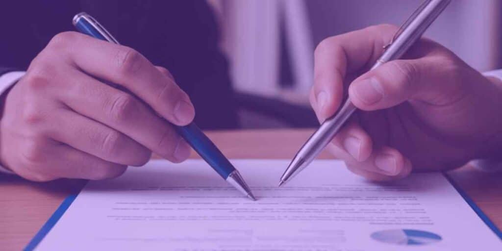 Um advogado mostrando ao seu cliente um documento de levantamento de bens para realizar o planejamento sucessório.